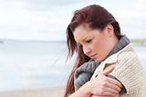 Worried woman wearing sweater on the beach and getting cold