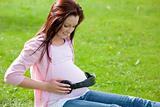Joyful pregnant woman with headphones on her belly