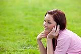 Delighted young woman on phone sitting on the grass