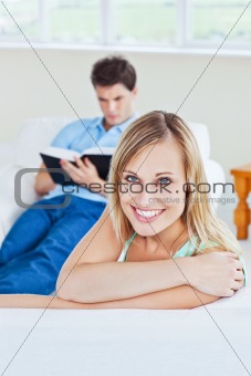 Girlfriend smiling at the camera while her boyfriend is focused 