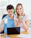 young couple drinking coffee and working together on the laptop 