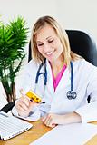 bright female doctor with stethoscope looking at pills 