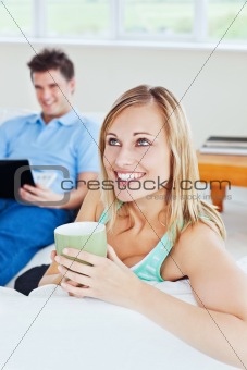 young couple. woman drinking tea when man using a laptop 