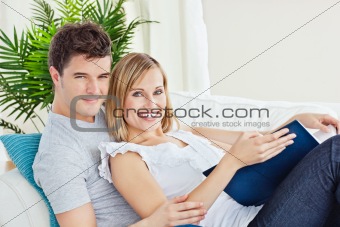 Young loving couple reading a book on the sofa