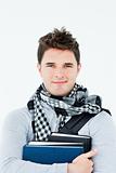Young man wearing a scarf squeezing books against himself