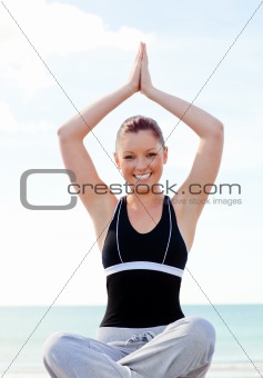 Young smilng woman doing exercise on the beach 