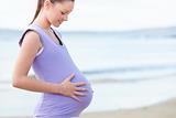 Pregnant smiling woman watching her stomach