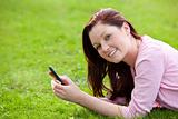 Attrative young pregnant woman lying on the grass texting