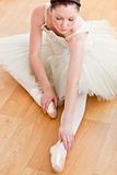 Radiant ballerina stretching on the floor 