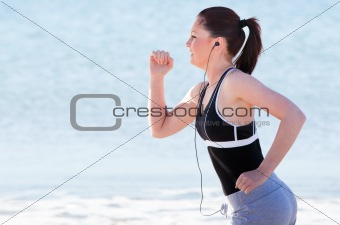 Young woman running on the beach listening music 