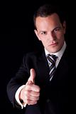 businessman giving consent, with thumb up, isolated on black background. Studio shot.