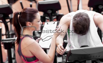 Female coach using a chronometer while man is pedaling on a bicy