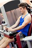 Serious athletic man using a leg press  in the weights room of a