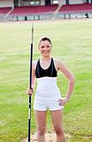 joyful sporty woman holding a javelin standing in a stadium