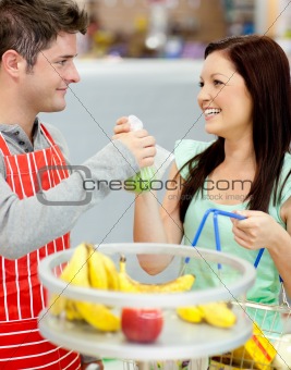 handsome salesman giving apples to a happy customer in a grocery