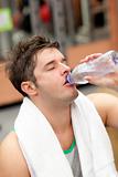 exhausted man drinking water with towel around the neck after a 