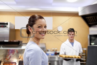 Beautiful woman in a cafeteria buying baguette from a baker stan