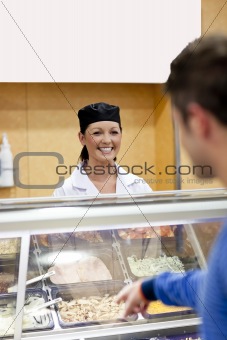 Handsome student showing his choice to the cook in the cafeteria