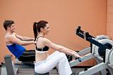 Young couple using a rower in a sport centre