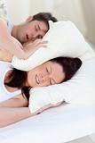 Young woman disturbed by snores putting her head under the pillow