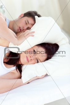 Young woman annoyed by the snores of her boyfriend in the bedroo
