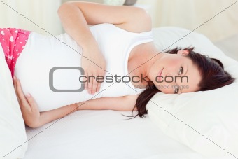 Portrait of a pregnant woman holding baby shoes and of her husband lying on the sofa
