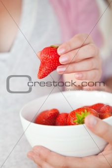 Close-up of a pregnant woman eating a bowl of strawberries