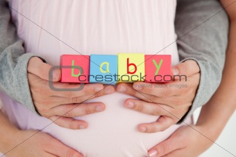 Close-up of the belly of a pregnant woman and of her husband hol