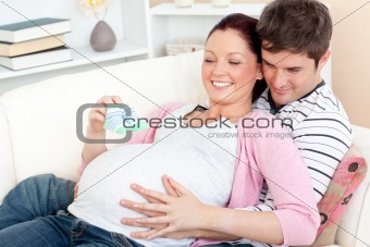 Portrait of a happy pregnant woman holding baby shoes and of her