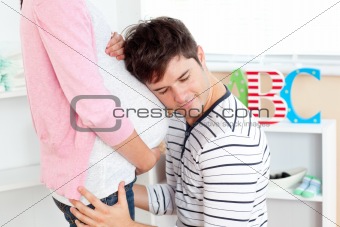 Close-up of a lovely man with head on his pregnant woman\'s belly