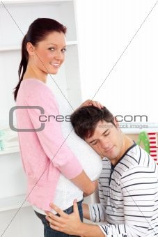 Portrait of an kind man with head on his pregnant woman's belly