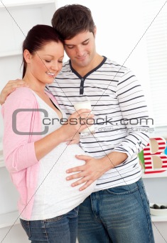 Portrait of a delighted pregnant woman holding a glass of milk