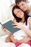 Close-up of a pregnant woman and her husband reading a book