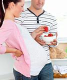 Man giving strawberries to his pregnant wife