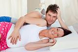 Happy future parents lying on the bed during the morning smiling