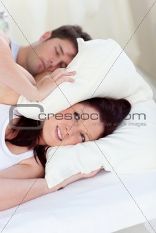 stressed future mom with head under the pillow in bed with her h