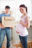 adorable pregnant woman with husband holding cardboard