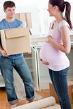 cute pregnant wife looking at her husband holding box standing i