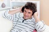 funny man listening music with headphones on sitting in his livi