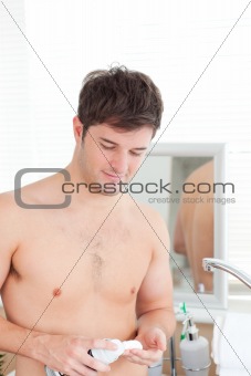 happy man putting shaving-foam standing in his bathroom