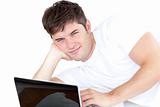 attractive young man using his computer lying on the floor