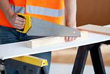 Close-up of a male worker sawing a wooden board
