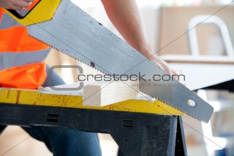 Close-up of a serious male worker sawing a wooden board