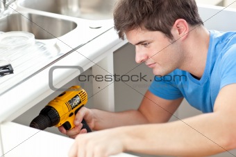 Assertive man holding a drill repairing a kitchen