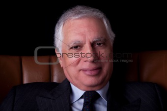 old businessman  seated on a chair with, isolated on black background, Studio shot
