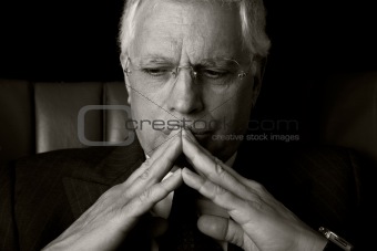 old businessman  seated on a chair, thinking, isolated on black background, Studio shot