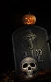 Spooky tombstone with skull and pumpkin on black