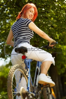 young adult smiling biker woman on mounting bike 