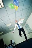 businessman flying in office with balloons