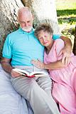 Senior Couple Reading Together Outdoors